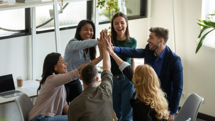 A happy group of young co-workers celebrating in a conference room.