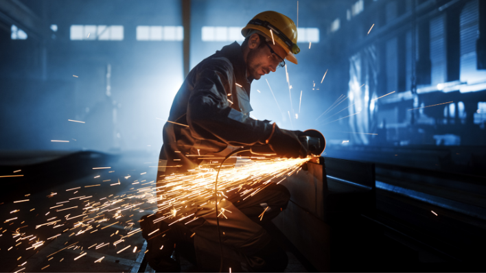 male wearing hardhat drilling with sparks