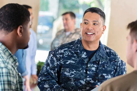 An image of two men speaking with military man
